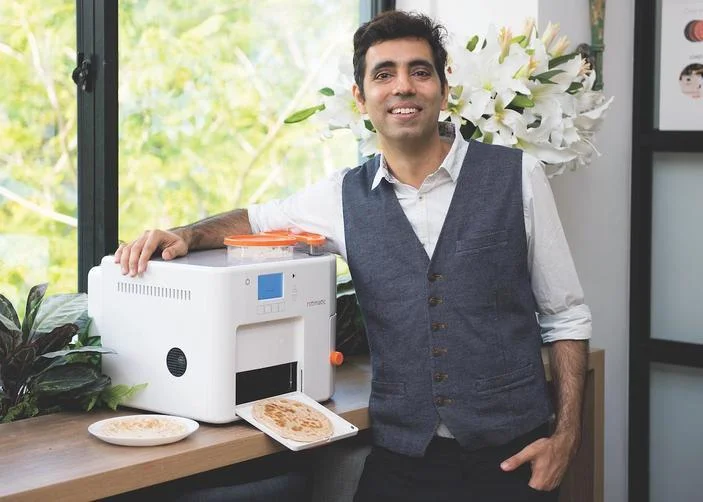 Rishi Israni de pie junto a su máquina Rotimatic Roti