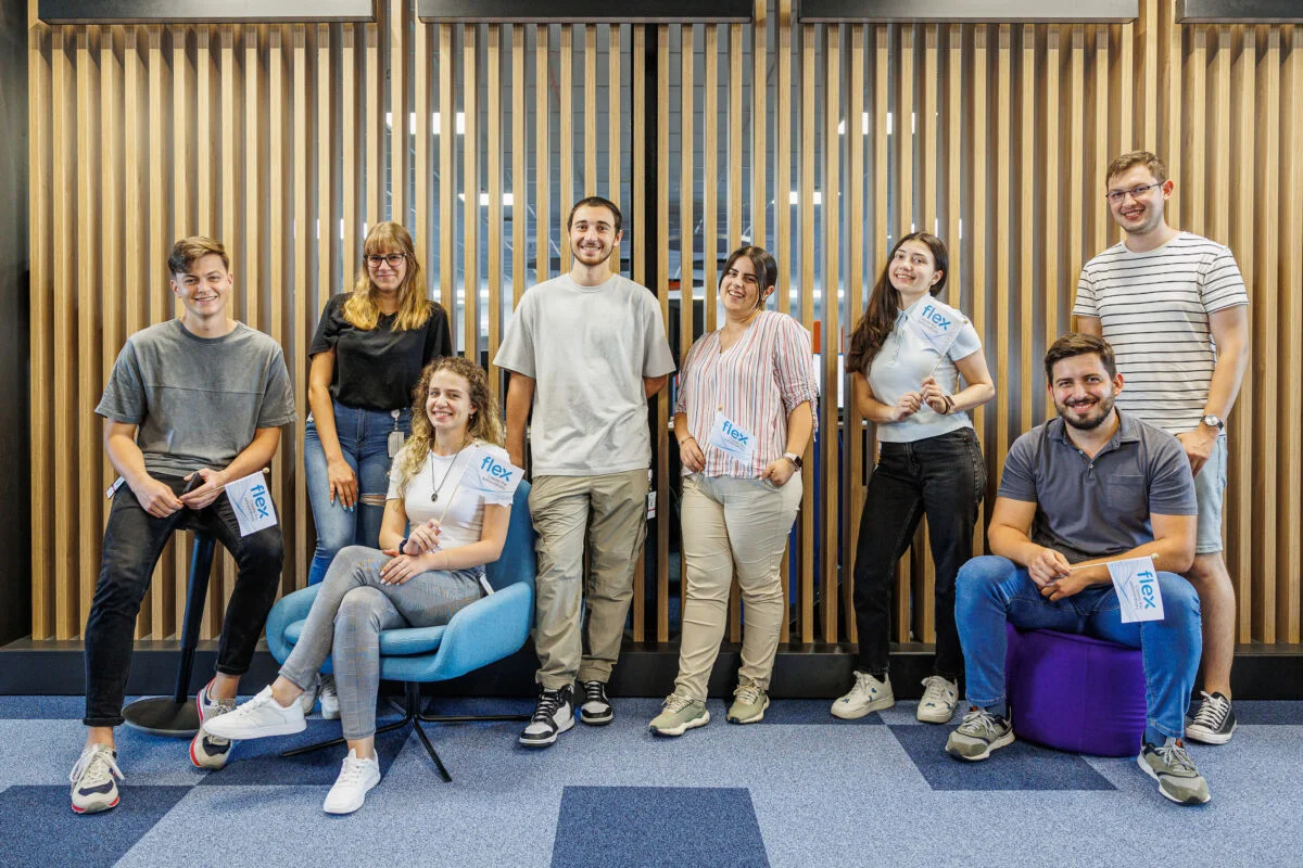 Gruppenbild von Flex-Praktikanten, die an einer Wand sitzen und stehen