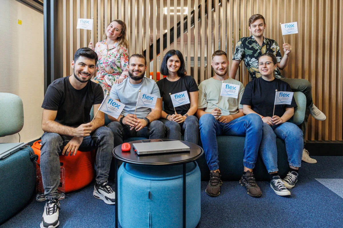 Gruppenbild von Flex-Praktikanten, die auf einem Sofa sitzen und Flex-Flaggen halten